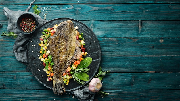 焼きヒラメの魚と野菜のブラックストーンプレートシーフードトップビューテキスト用の空きスペース