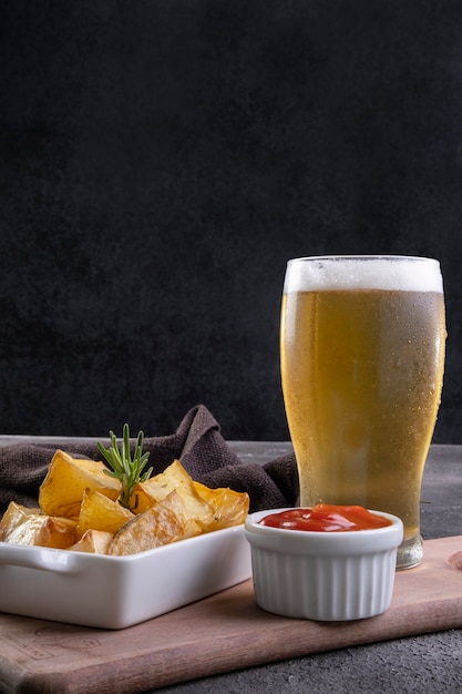 Baked fried potatoes with rosemary, coarse salt, olive oil and spice paprika in iron skillet and a pint of beer.