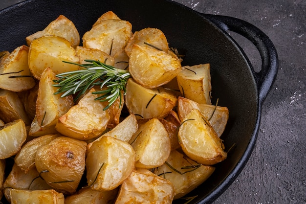 Baked fried potatoes with rosemary, coarse salt, olive oil and spice paprika in iron skillet.