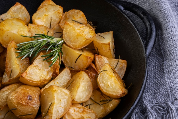 Baked fried potatoes with rosemary, coarse salt, olive oil and spice paprika in iron skillet.