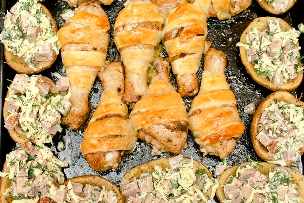 Baked fried roasted chicken legsdrumsticks meat wrapped in puff pastrydough pita bread and potatoes filled with sausages and cheese in ovenstep by step instruction