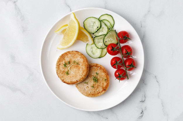 Baked Fried Salmon cutlets with vegetables tomatoes cherry cucumbers on plate