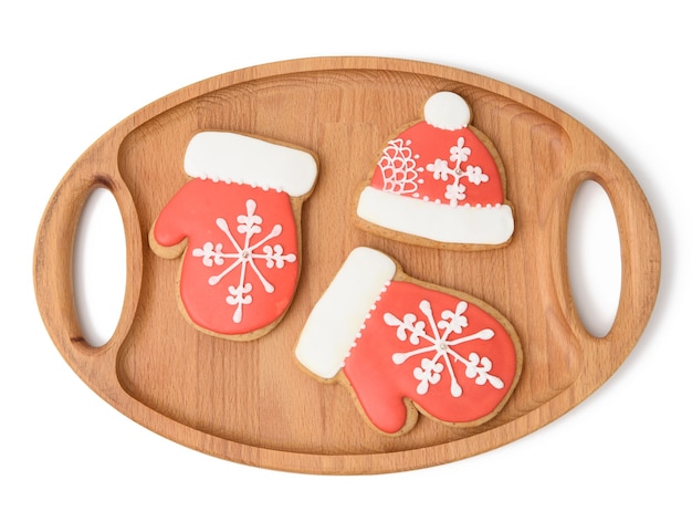 Photo baked gingerbread in the shape of a mitten and covered with red icing, classic christmas dessert on a wooden tray