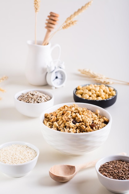 Baked granola in a bowl and different seeds in bowls on the table Healthy breakfast Vertical view