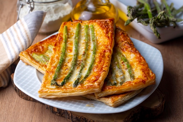 Photo baked green asparagus with ham and cheese in puff pastry sprinkled with sesame seeds and green basil leaves