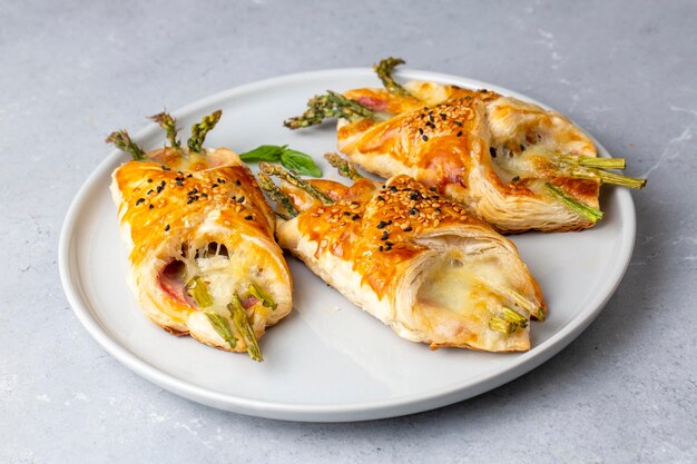 Baked green asparagus with ham and cheese in puff pastry sprinkled with sesame seeds