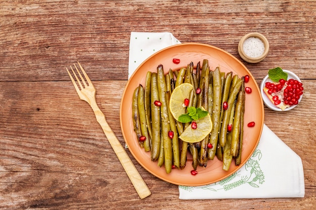 Baked green bean casserole topped with sesame seeds, pomegranate, mint and lemon