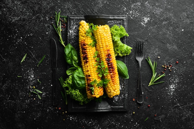 Baked grilled corn with spices and salt on a black stone plate Top view Free copy space