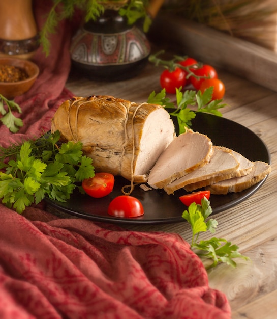 Baked ham on a plate with tomatoes and herbs