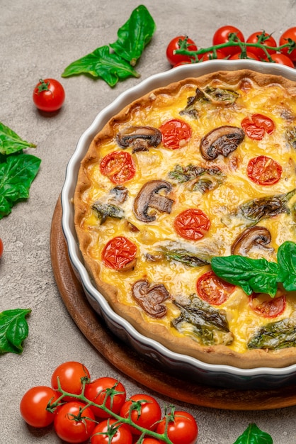 Baked homemade quiche pie in ceramic baking form on concrete background