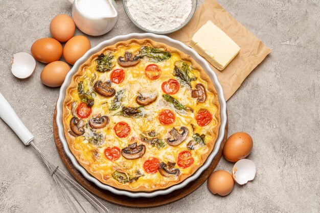 Baked homemade quiche pie in ceramic baking form, eggs and cream