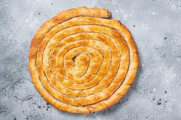 キッチンテーブルの上の自家製の伝統的なギリシャのチーズパイを焼いた灰色の背景上面図