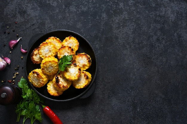 Baked hot corn with butter in a castiron pan on a black background View from above