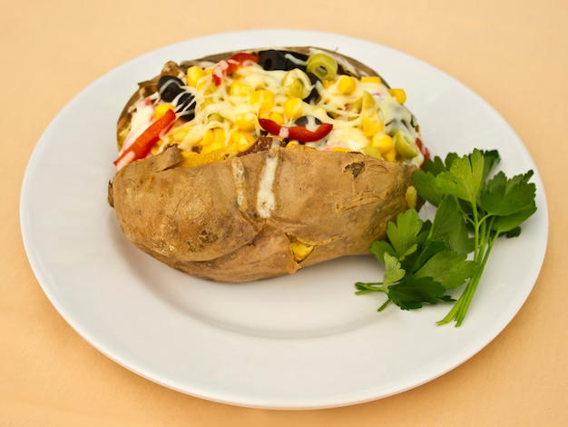 Baked kumpir potato stuffed with cheese, sausage, olives, peppers and corn