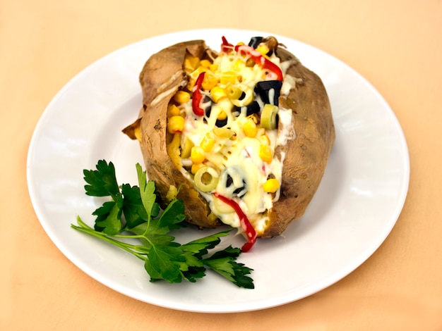 Baked kumpir potato stuffed with cheese, sausage, olives, peppers and corn