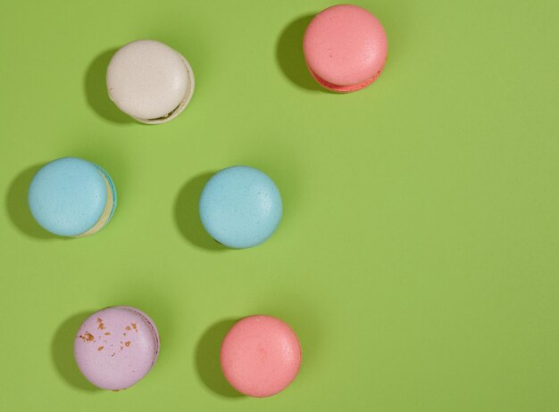 Macarons al forno con gusti diversi su sfondo verde, vista dall'alto