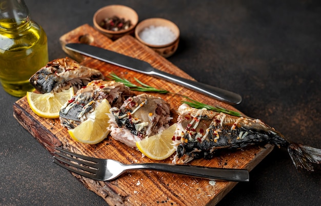 baked mackerel on a cutting board with lemon and spices on a stone background