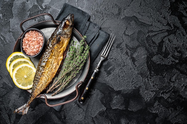 Baked Mackerel Scomber fish in steel tray with thyme and lemon Black background Top view Copy space