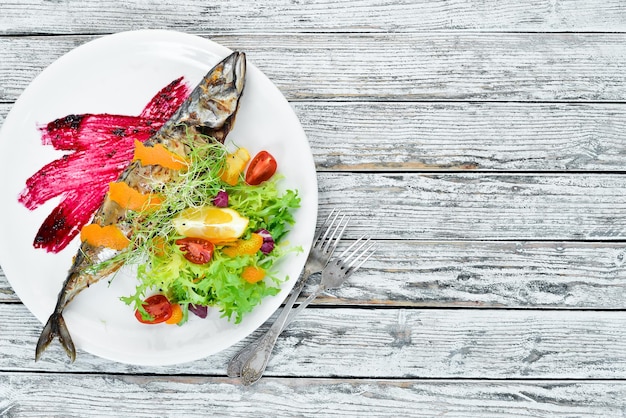 Photo baked mackerel with fresh vegetables on the plate top view free space for your text