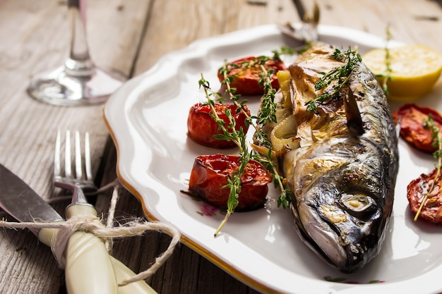 Photo baked mackerel with tomato and lemon in a vintage plate