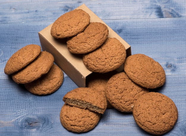 Concetto di pasto al forno biscotti di farina d'avena come gustosa pasticceria per il presente panetteria dolce e deliziosi spuntini biscotti su scatola di cartone su sfondo grigio di legno