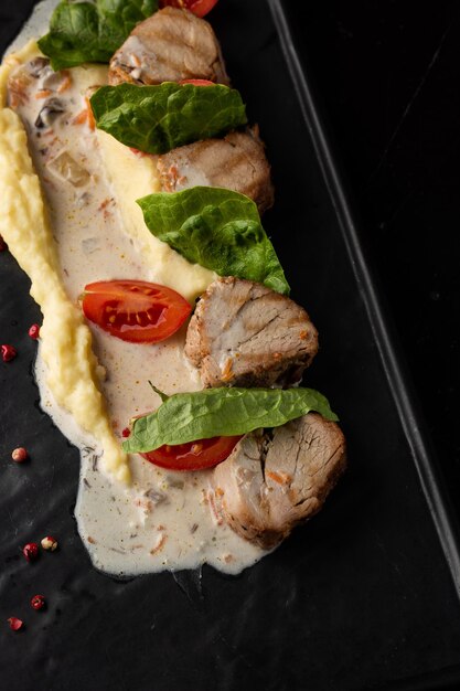 Baked meat and mashed potatoes as a garnish in white plate Macro closeup on a black background Delicious meal restaurant menu concept