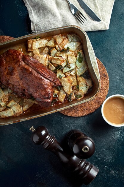 Baked meat and potatoes. A delicious and hearty meal. A large baked piece of meat. Cooked hot food.