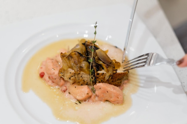 Baked meat with rosemary and sauce people making meal together\
awaiting guests concept of home cooking healthy food a cook checks\
the readiness of meat with a knife and fork