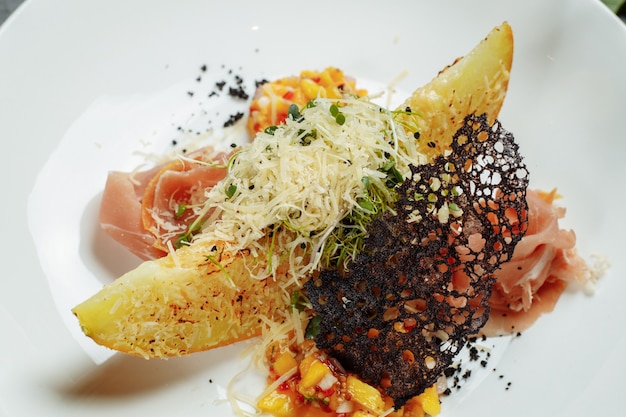 Baked melon with parmesan and jamon on a white plate