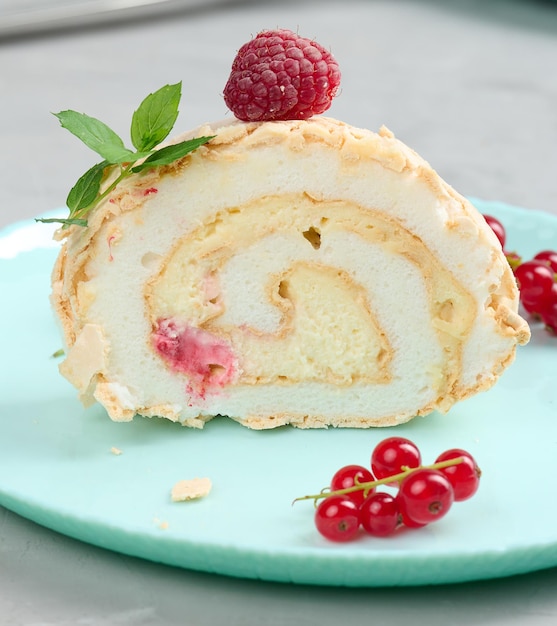 Rotolo di meringa al forno con bacche rosse su fondo bianco piatto rotondo