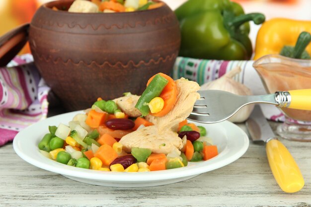 Baked mixed vegetable with chicken breast in pot on bright background