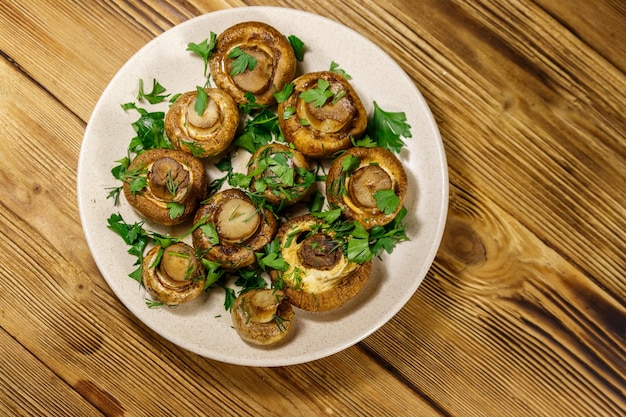 Baked mushrooms in plate on wooden table Top view