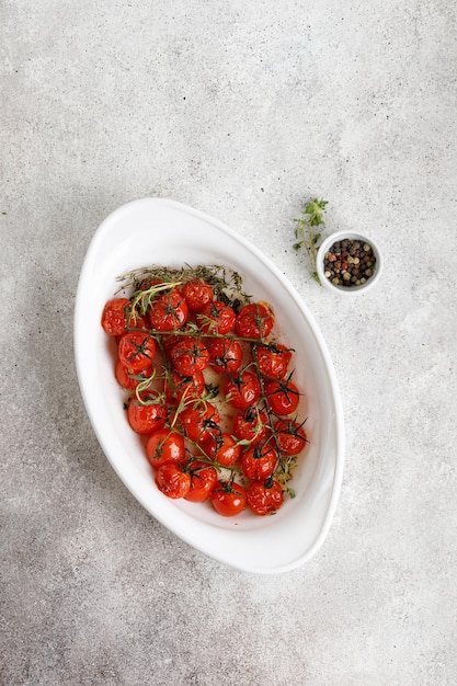 Baked in oven Cherry Tomatoes with spices garlic herbs garlic olive oil in a white dish Top view