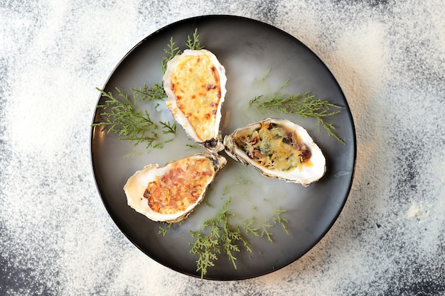 Baked oysters with cheese in a black plate