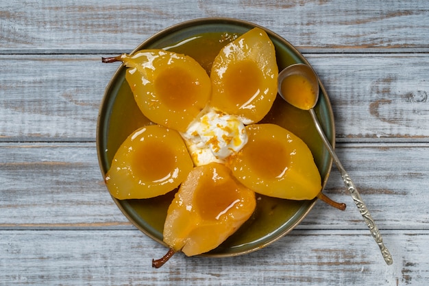 Baked pears in orange juice with ice cream, close up, top view. Delicious dessert.