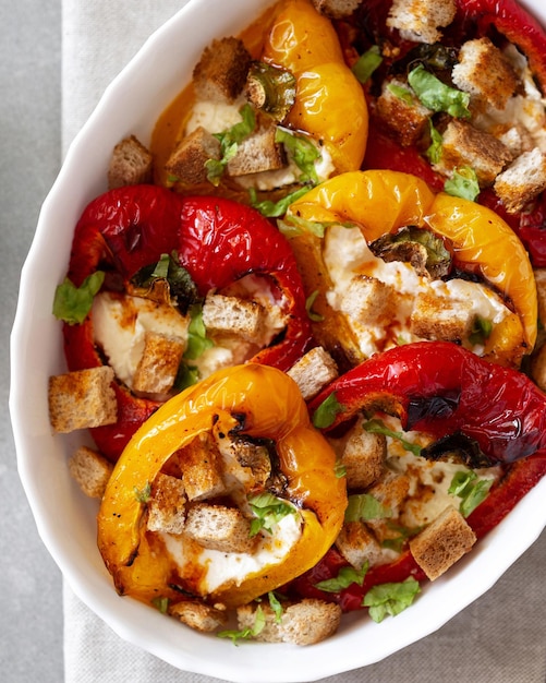 Baked peppers with cream cheese on a gray concrete background Grilled colorful peppers with cream cheese and croutons Delicious homemade picnic food