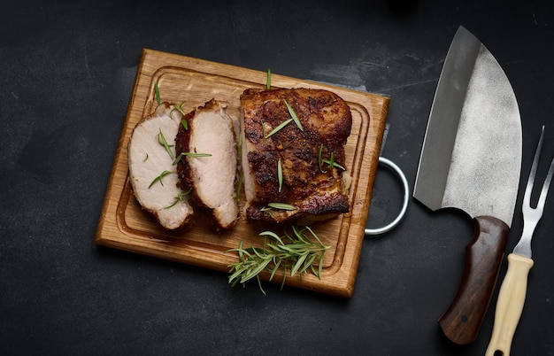 Baked piece of pork meat in spices on a wooden board cut into pieces Eye of round roast steak