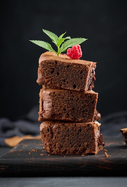 Baked pieces of chocolate brownie pie on black table delicious dessert