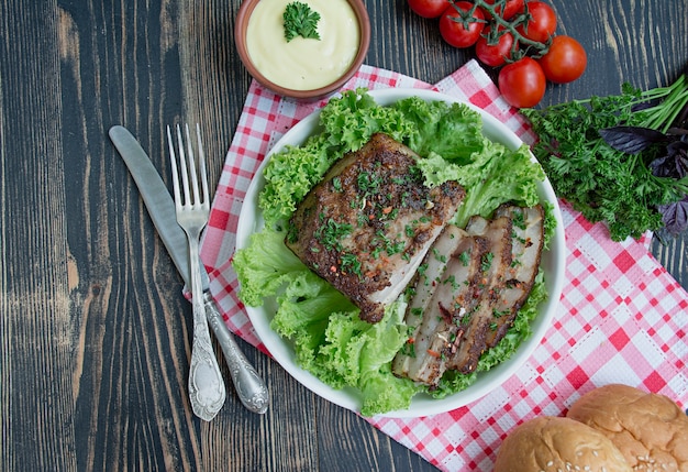 Baked pork belly with spices. Sliced breast, served with greens. Traditional dish of Ukraine.