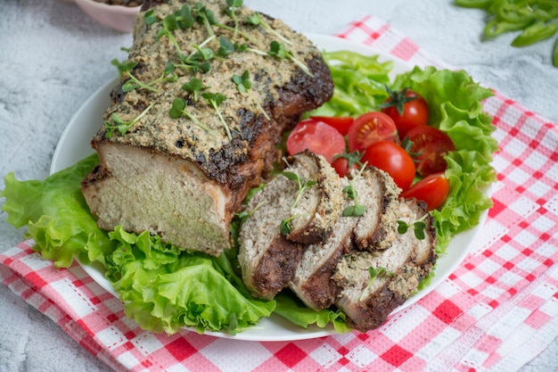 Baked pork chopped in a sauce of walnuts and mint on a white plate with fresh herbs and vegetables