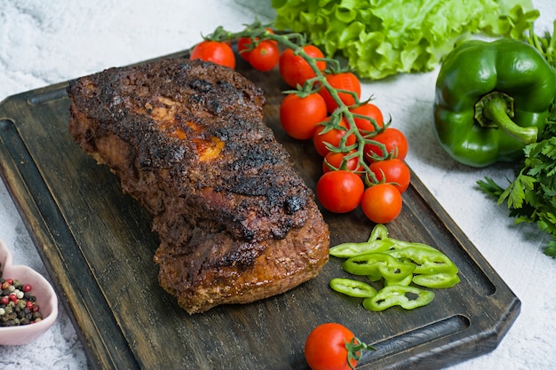 Baked pork chopped in a walnut and mint sauce on a cutting board with fresh herbs and vegetables.