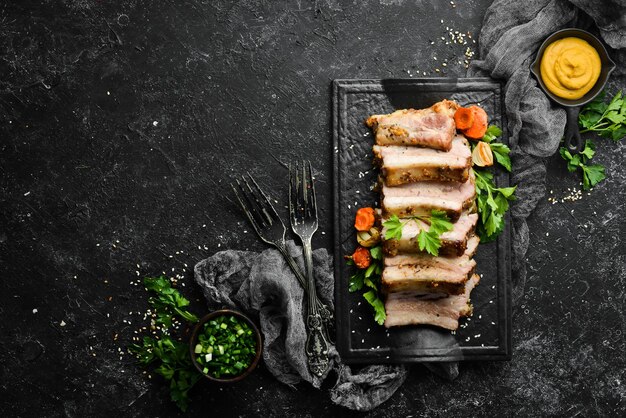 Baked pork ribs with mustard and spices on a black stone plate Top view Free space for text