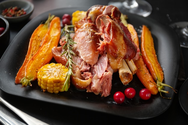 Baked pork with vegetables and spices on plate. Closeup