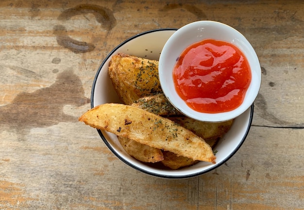 Baked potato slices and spices and ketchup on wooden table background. vegan potato wedges homemade