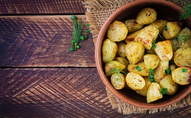 Запеченные картофельные дольки в миске на деревянном столе. Вкусный обед. Вид сверху, сверху