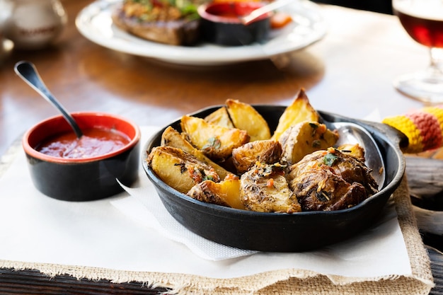 Baked potato wedges with herbs and sauce in a frying pan at a restaurant