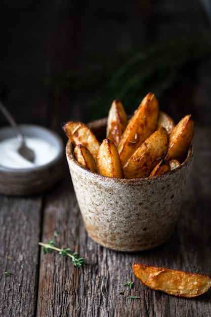 baked potato wedges with sauce on a dark wooden surface