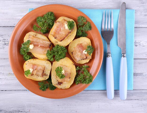 Photo baked potato with bacon on plate on wooden background