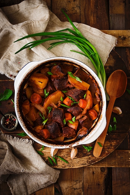 Baked potato with beef Bourguignon on the old wooden table in rustic style