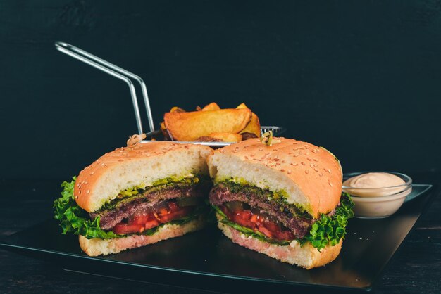 Baked potatoes and Burger with meat, tomatoes and onions. On a wooden background. Free space for text. Top view.